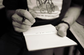 B&W photo of hands writing on paper