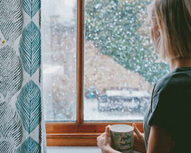 Woman looking out rainy window