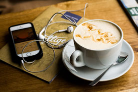 iPhone on table with earbuds and latte